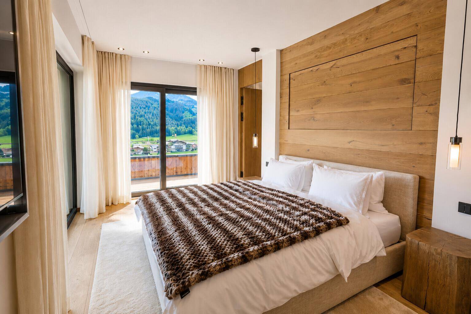 Helles Schlafzimmer mit Holzwand, großem Bett und Zugang zu einem Balkon mit Bergblick.