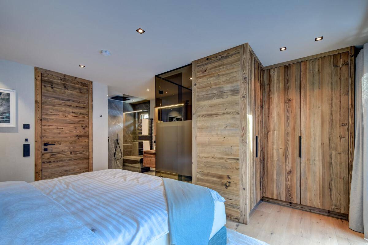 Schlafzimmer mit Holzwänden, Einbauschränken und integriertem Badezimmerbereich.