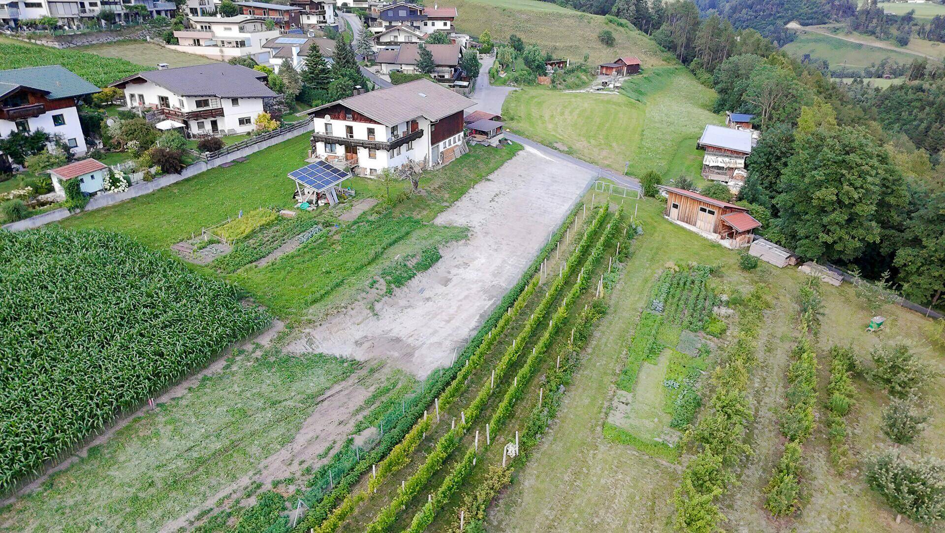 Luftaufnahme eines Anwesens mit Wohnhaus, landwirtschaftlichen Flächen und Weinreben.