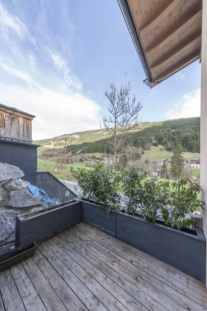 Kleiner Holzbalkon mit Pflanzenkübeln und weitem Blick auf die Berglandschaft.