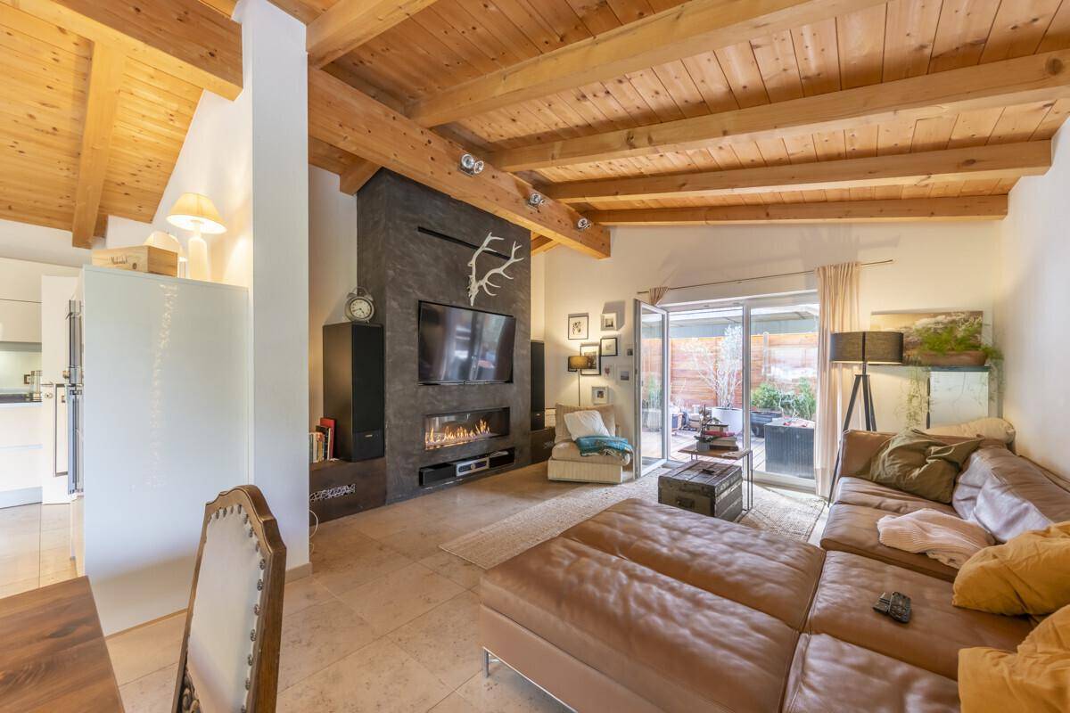 Gemütliches Wohnzimmer mit großem Sofa, modernem Kamin und Holzbalkendecke.