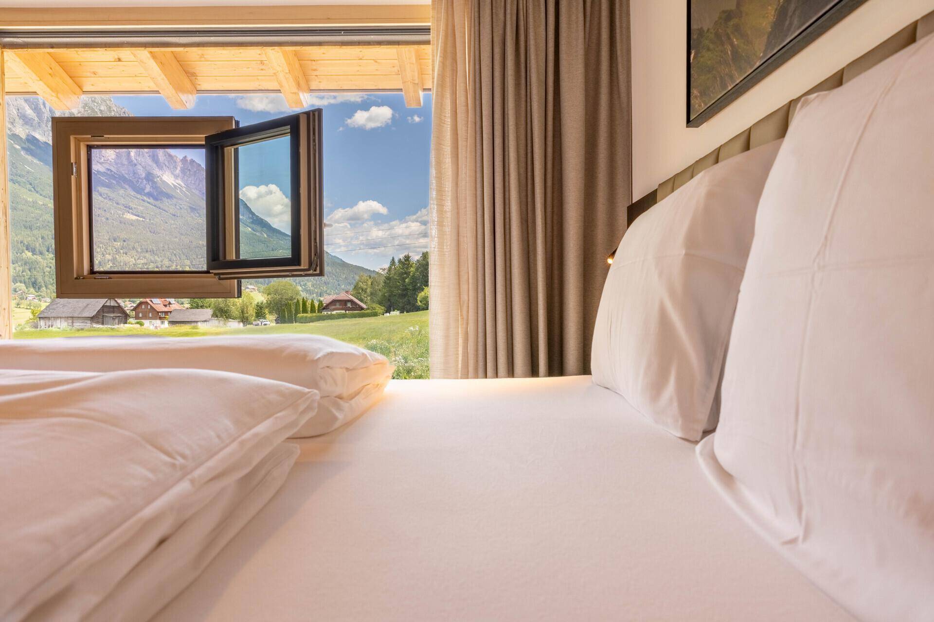 Schlafzimmer mit Doppelbett und Panoramablick auf die Berge und grüne Landschaft.