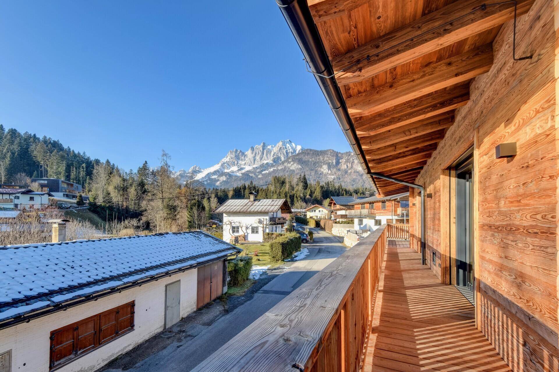 Langer Holzbalkon mit Bergblick und viel Sonnenschein, ideal für Outdoor-Living und Entspannung.