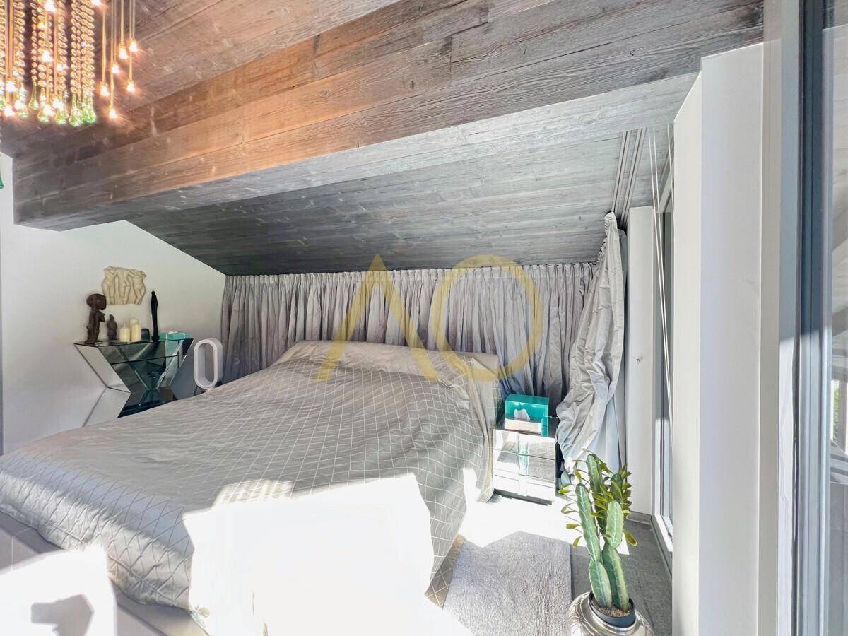 Gemütliches Schlafzimmer mit Holzbalkendecke, großen Fenstern und viel Tageslicht.