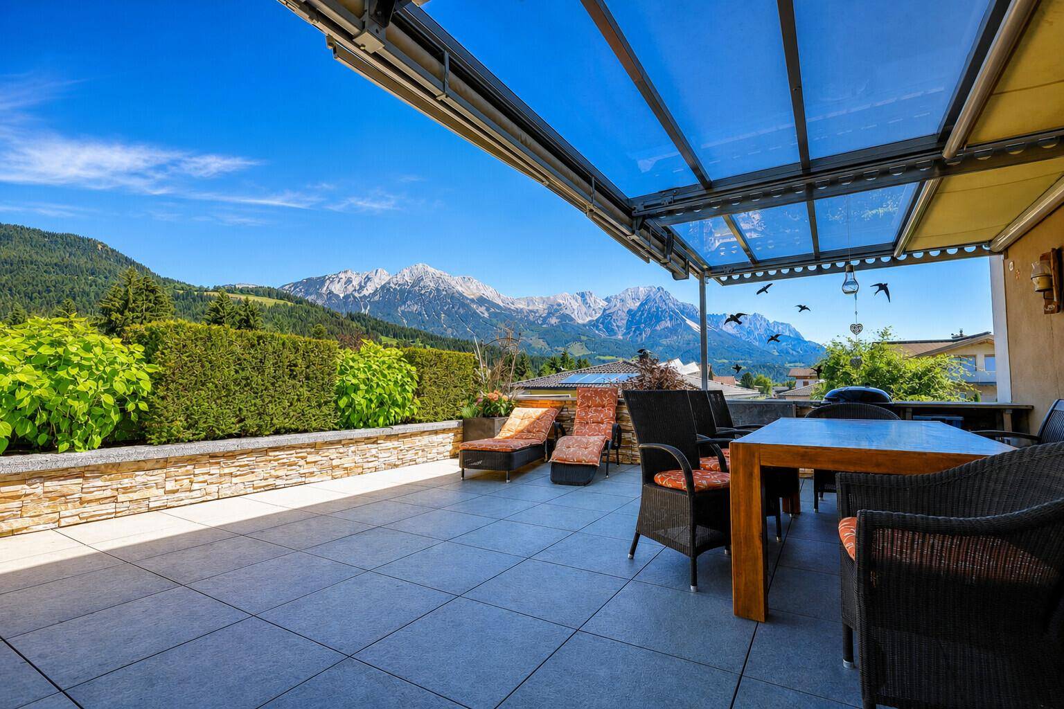 Geräumige Terrasse mit modernen Gartenmöbeln und einem atemberaubenden Blick auf die umliegenden Berge.