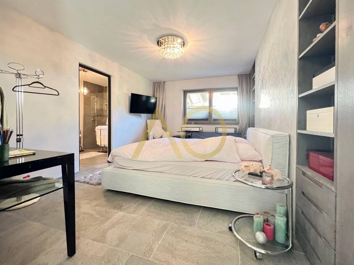 Helles Schlafzimmer mit modernem Bett, Einbauschränken und Blick auf die Umgebung.