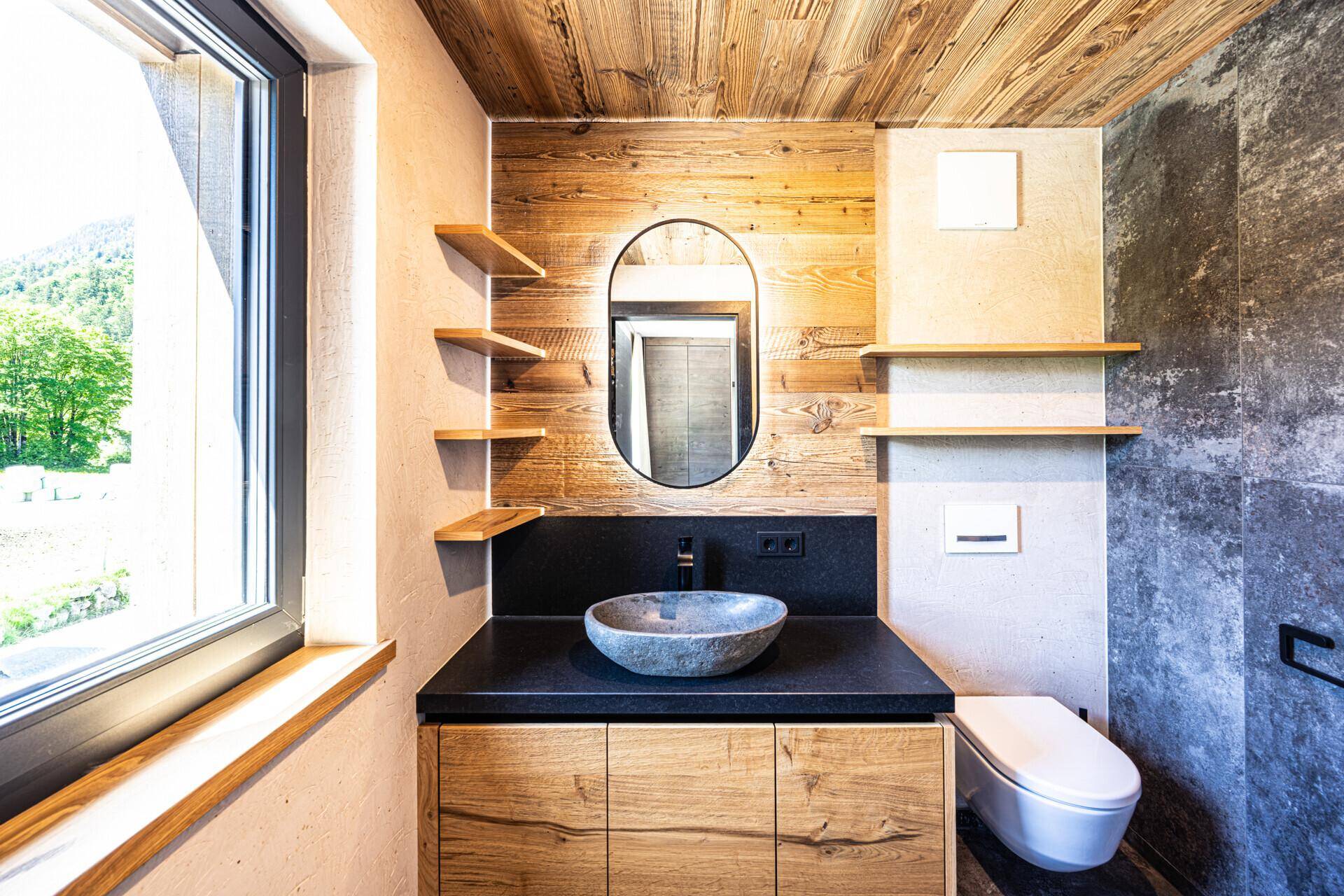 Modernes Badezimmer mit Holzdetails, Steinsink und Fenster für natürliches Licht.