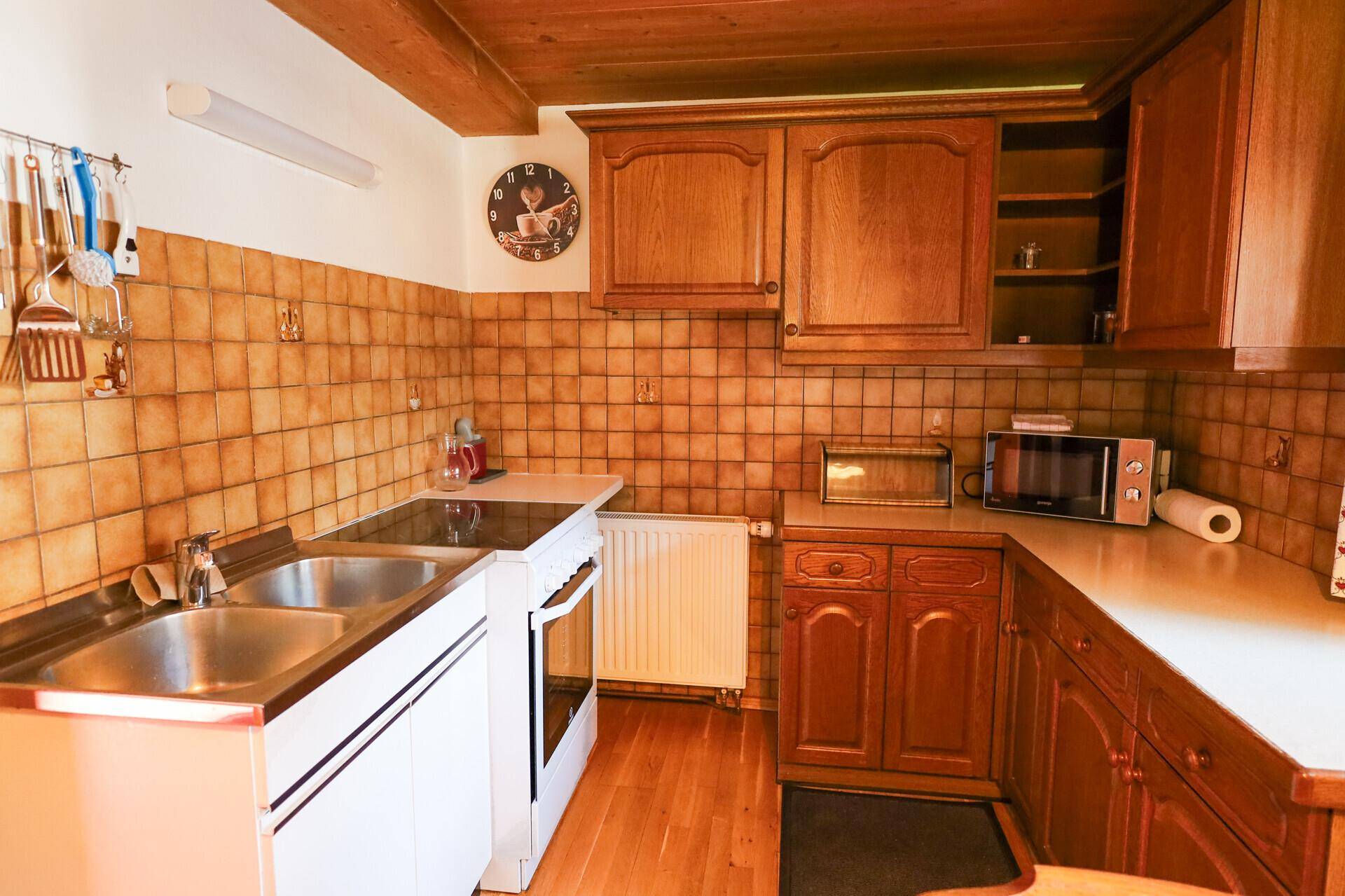 Funktionale Küche mit Holzschränken, gefliestem Spritzschutz und grundlegenden Küchengeräten.