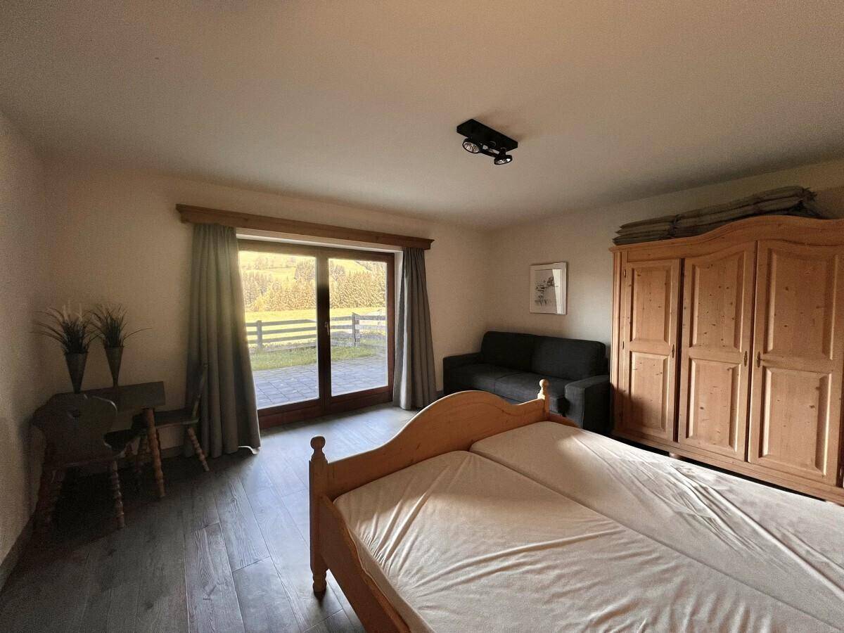 Schlafzimmer mit Holzbetten, großem Holzschrank und direktem Zugang zur Terrasse.