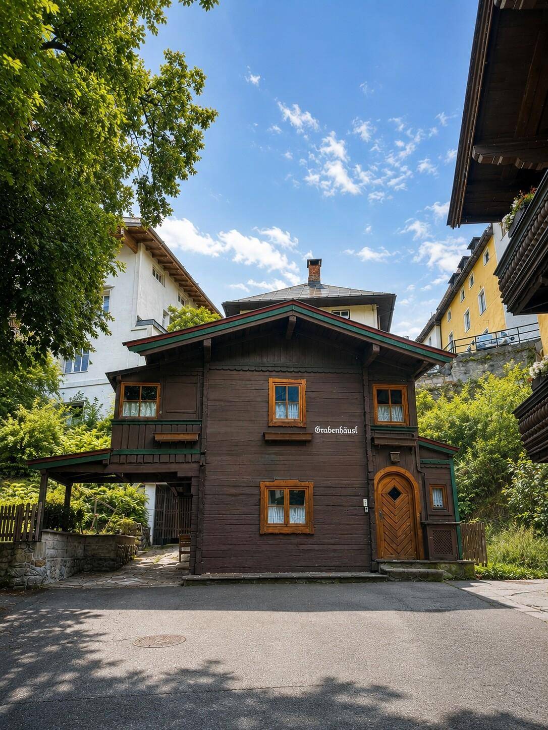 Traditionelles Holzhaus im Chalet-Stil mit dunkler Fassade und Holztüren unter strahlend blauem Himmel.