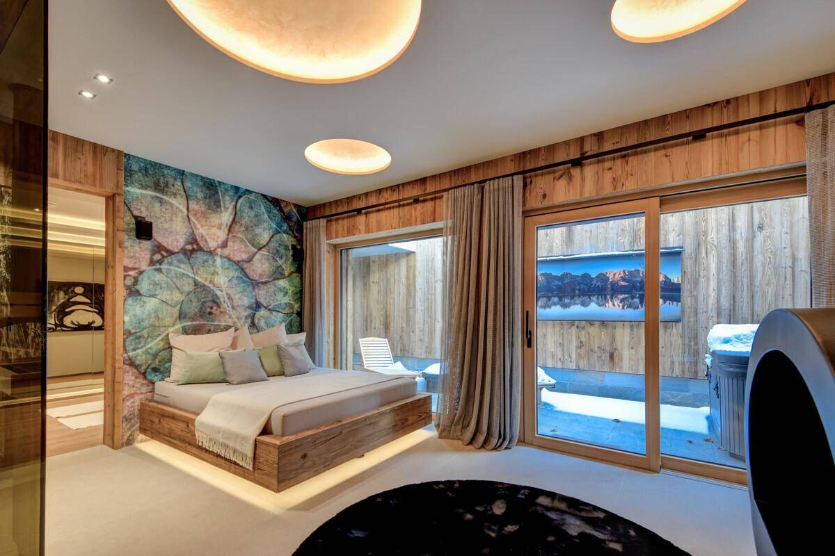 Einzigartiges Schlafzimmer mit Holzbett, großer Fensterfront und Zugang zu einem privaten Außenbereich.