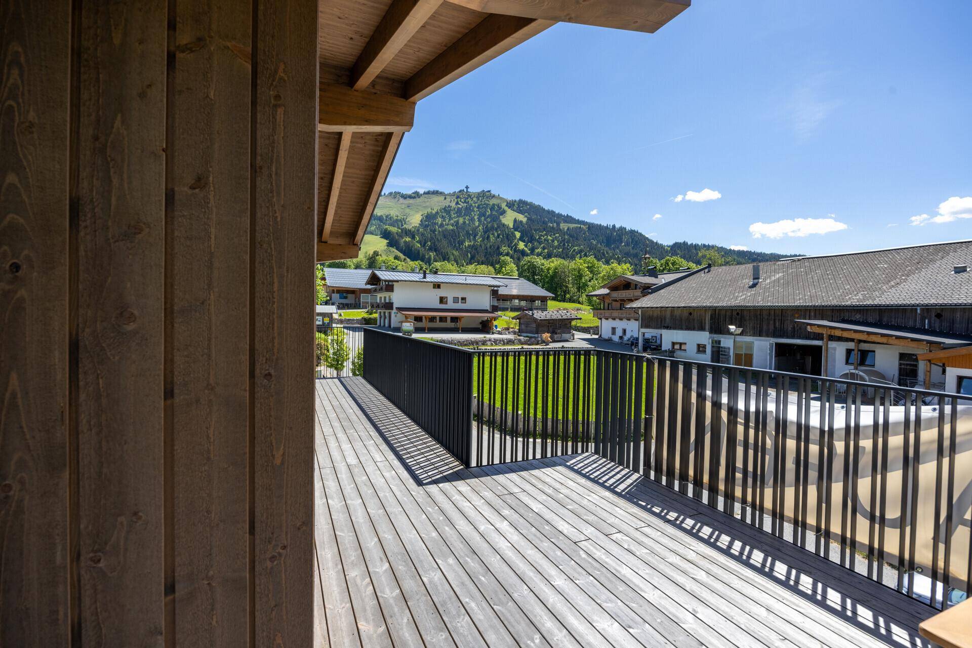 Geräumiger Holzbalkon mit Blick auf die umliegende Berglandschaft und andere Gebäude.