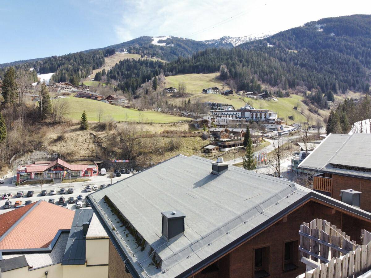Panoramablick über die Dächer der Häuser und die majestätische Bergkulisse mit bewaldeten Hängen.