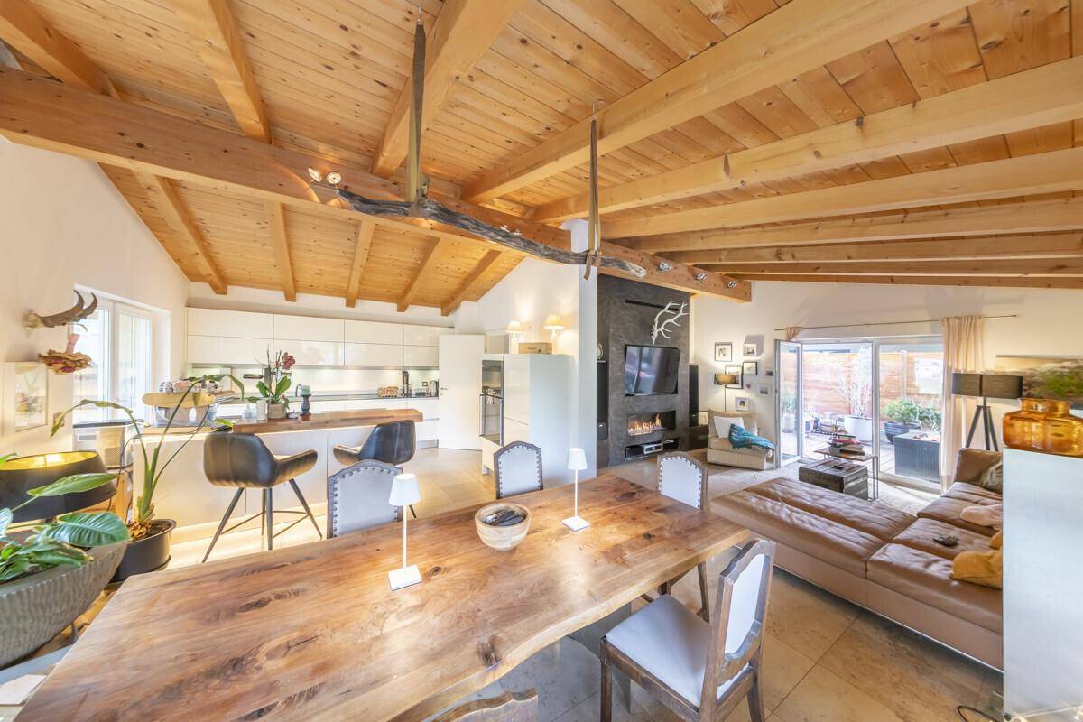 Geräumiger Wohn-Essbereich mit Holzbalkendecke, moderner Küche und Zugang zur Terrasse.