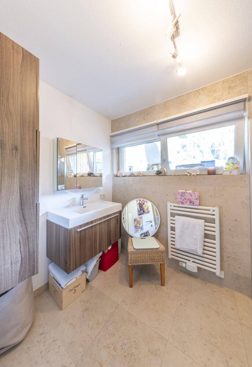 Modernes Badezimmer mit Einzelwaschbecken, Fenster und beheiztem Handtuchhalter.