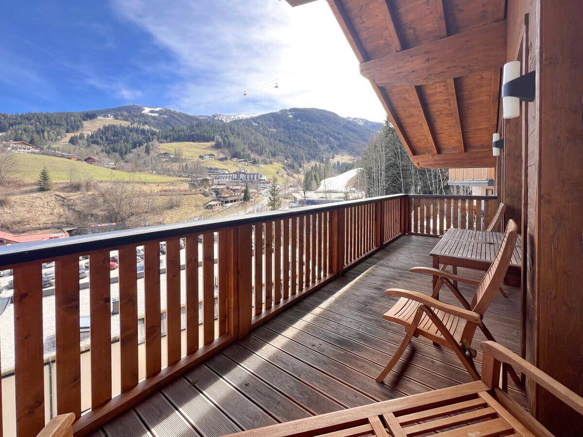 Geräumiger Balkon mit Holzboden und Sitzgelegenheiten, bietet einen weiten Blick auf die Berge.