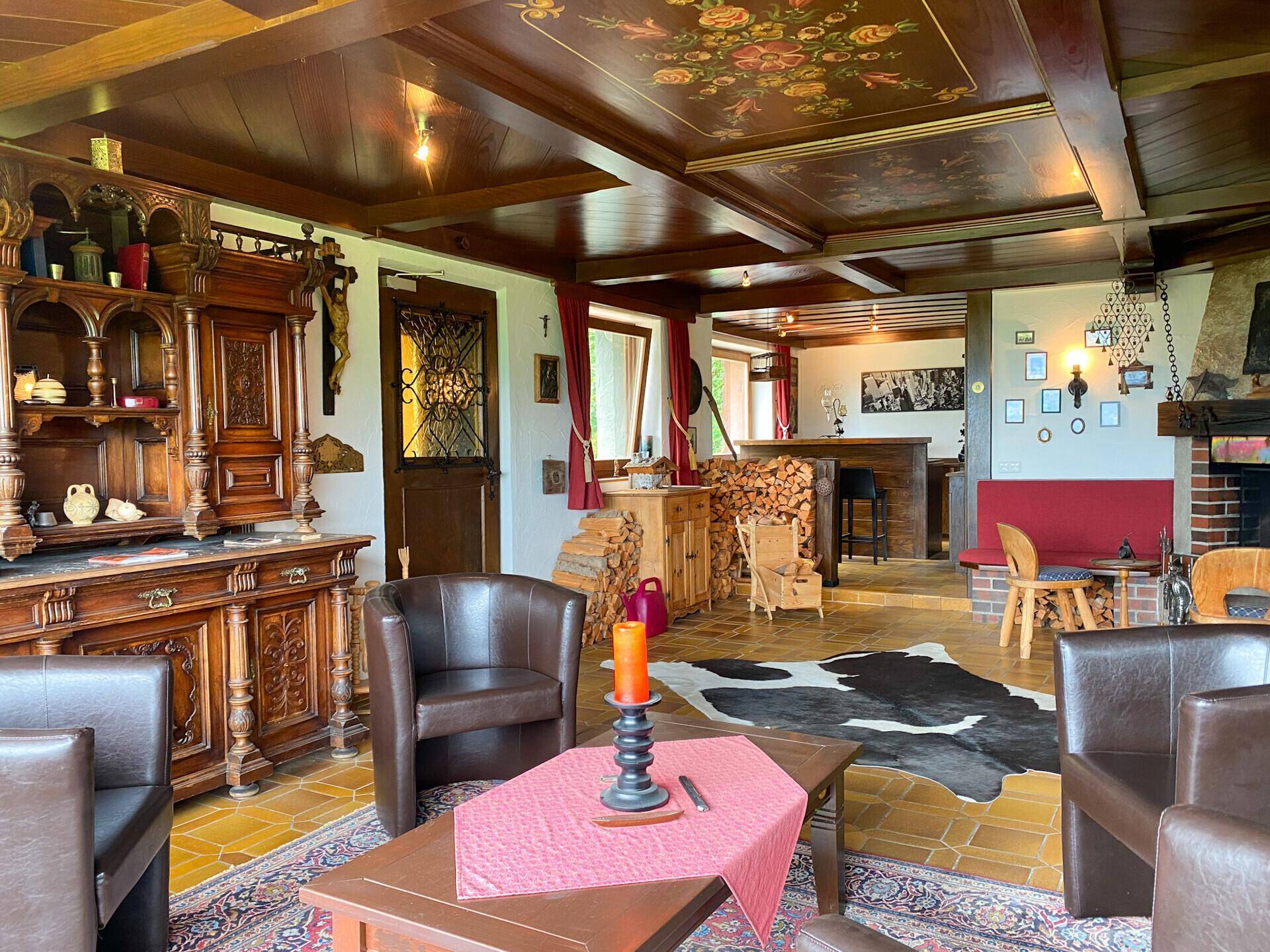 Geräumiger Wohnbereich mit traditionellen Holzmöbeln, bemalter Decke und einer Bar im Hintergrund.