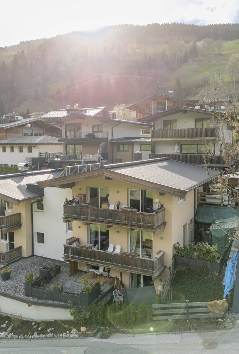 Mehrstöckiges Wohngebäude mit Balkonen und Terrassen in einer grünen Umgebung.