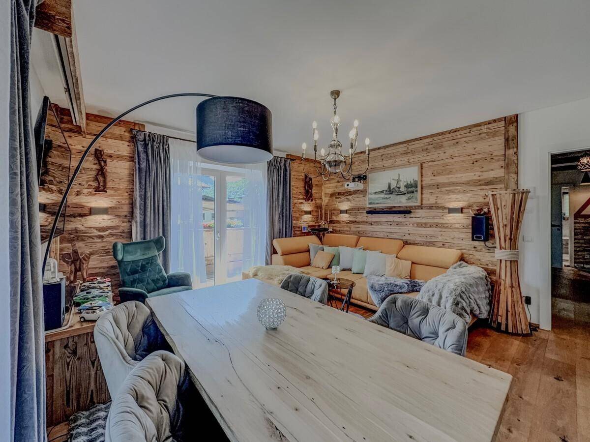 Heller Wohn-Essbereich im Chalet-Stil mit Holzwänden, großem Esstisch und moderner Beleuchtung.