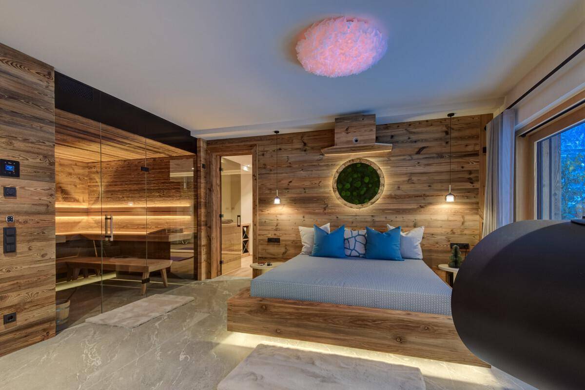 Schlafzimmer mit Holzwänden, integrierter Sauna und stilvoller Beleuchtung.
