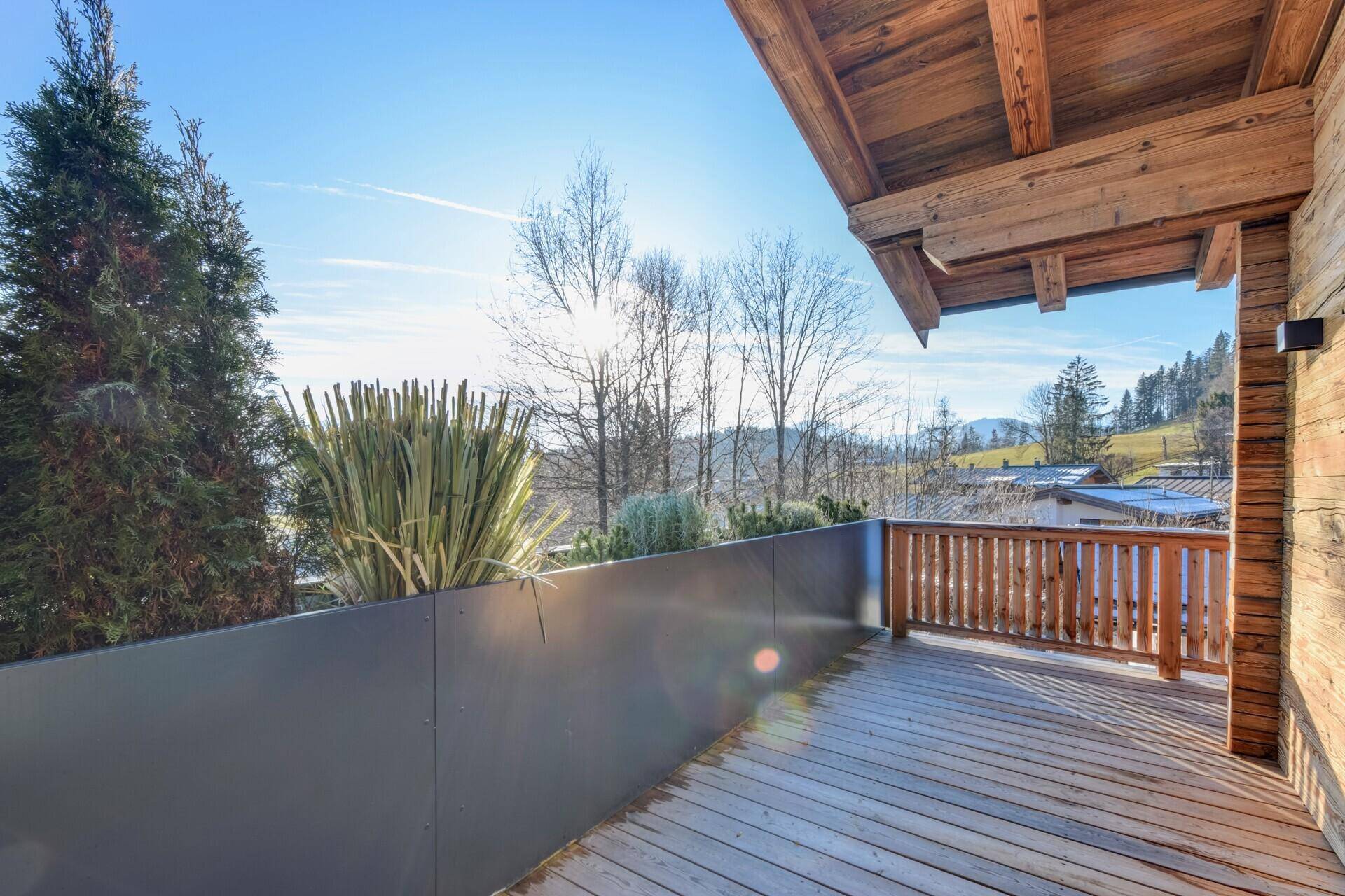 Geräumiger Holzbalkon mit Blick auf die Umgebung und viel Sonnenschein.