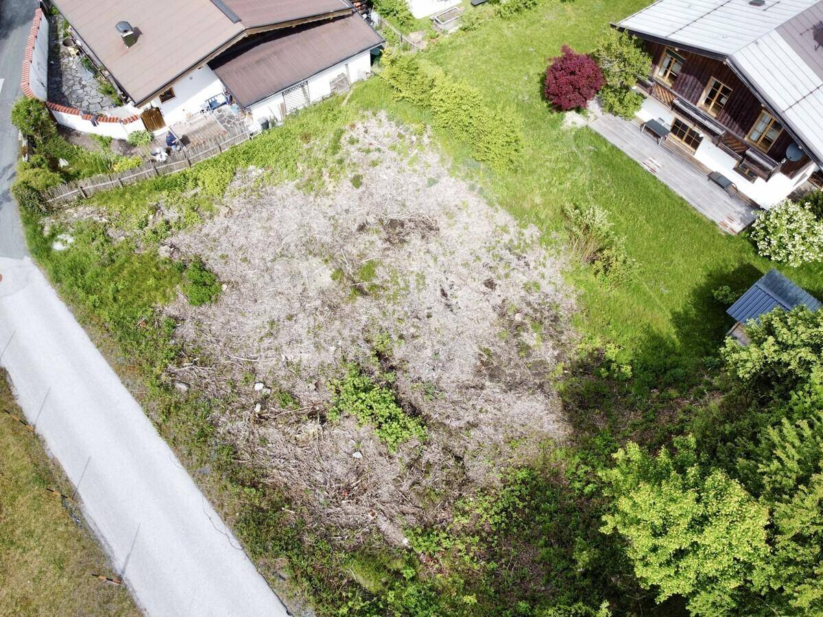 Luftaufnahme eines gerodeten Grundstücks, umgeben von grünen Wiesen und benachbarten Häusern.