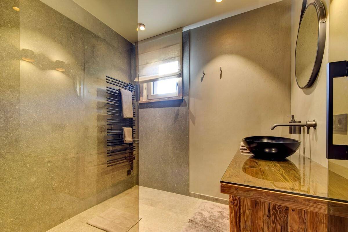 Modernes Badezimmer mit Einzelwaschbecken, begehbarer Dusche und beheiztem Handtuchhalter.
