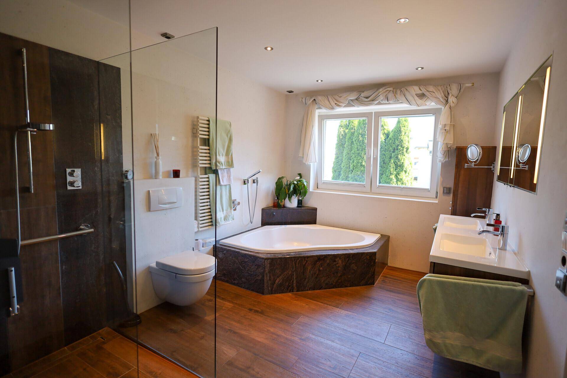 Modernes Badezimmer mit Eckbadewanne, großer Dusche, Doppelwaschbecken und Fenster.
