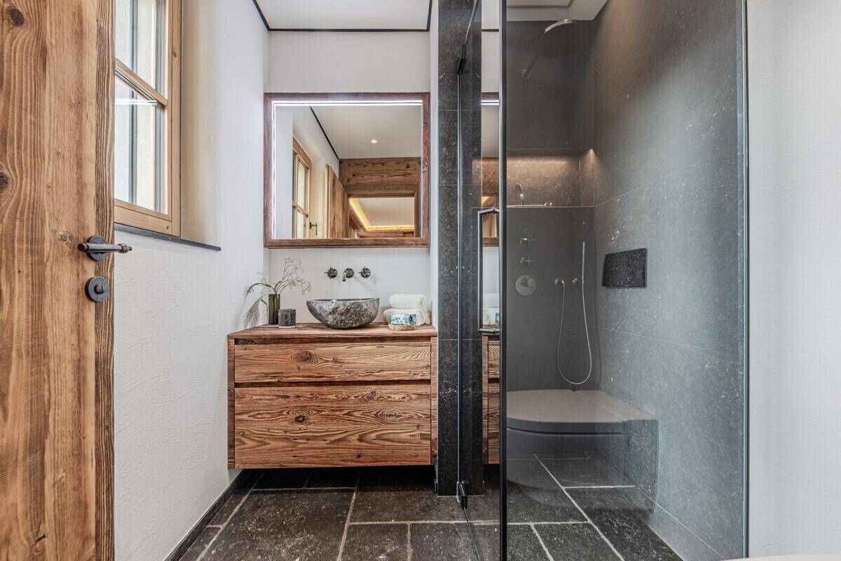 Modernes Badezimmer mit Holzelementen, Steinfliesen und einer begehbaren Dusche.