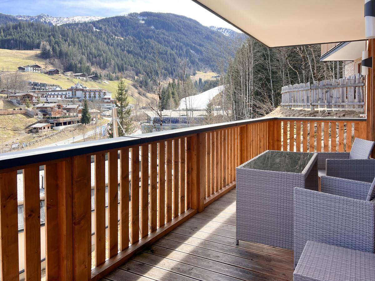 Sonniger Balkon mit bequemen Outdoor-Möbeln und einem weiten Blick auf die Berglandschaft.
