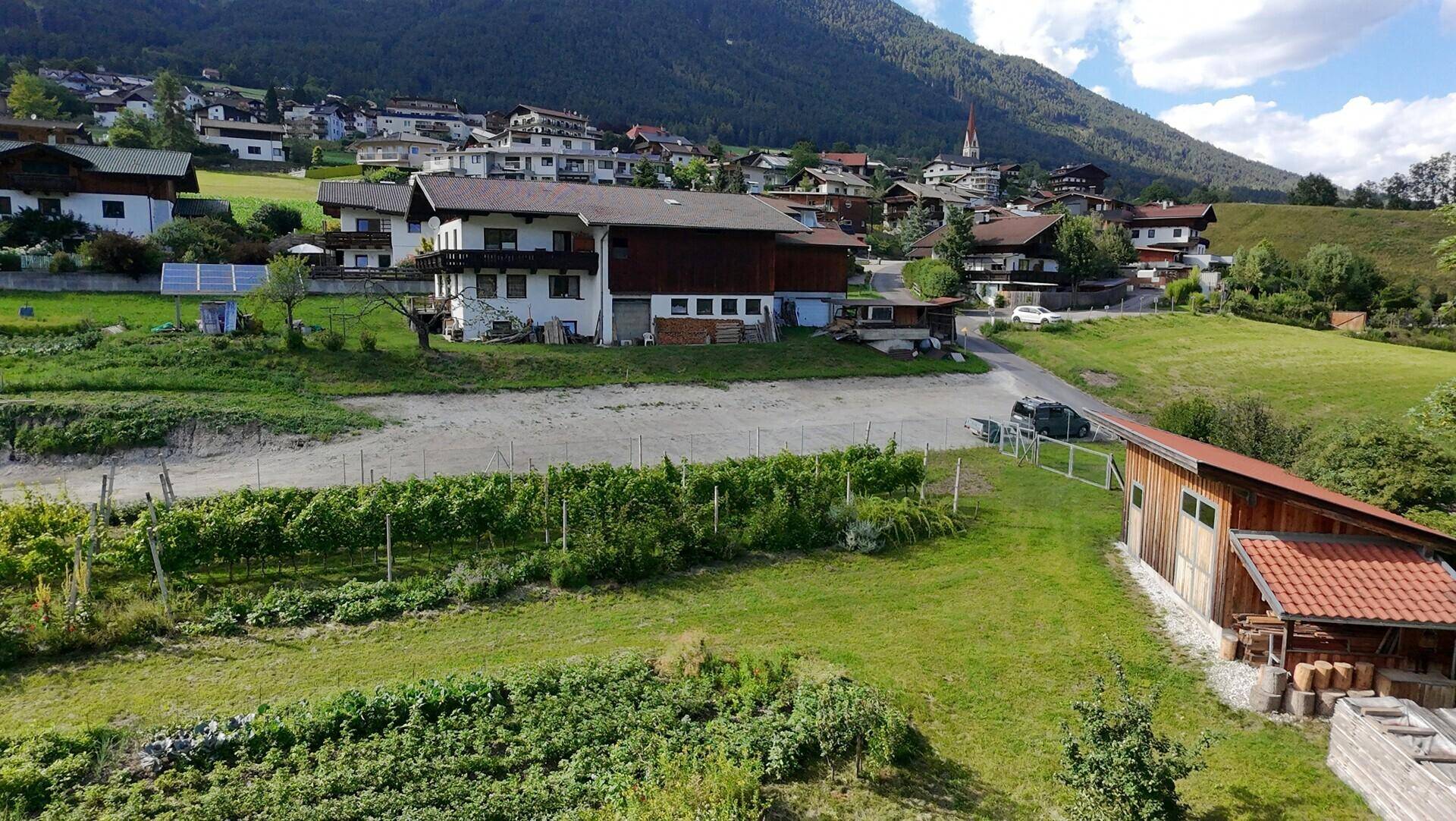 Luftaufnahme eines Dorfes mit Häusern, Feldern, Weinbergen und ländlicher Umgebung.