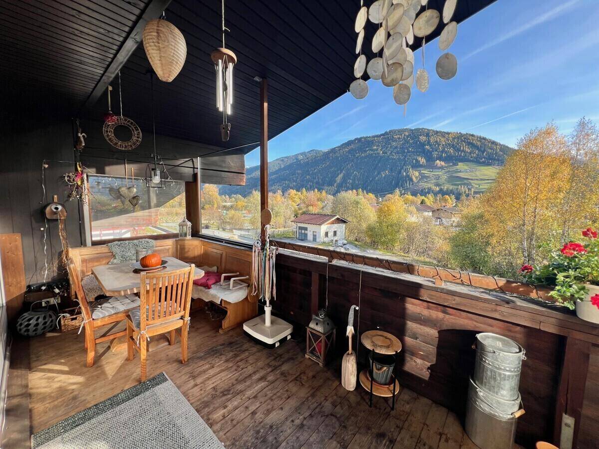 Gemütlicher Balkon mit Esstisch, Dekoration und Panoramablick auf die umliegende Berglandschaft.