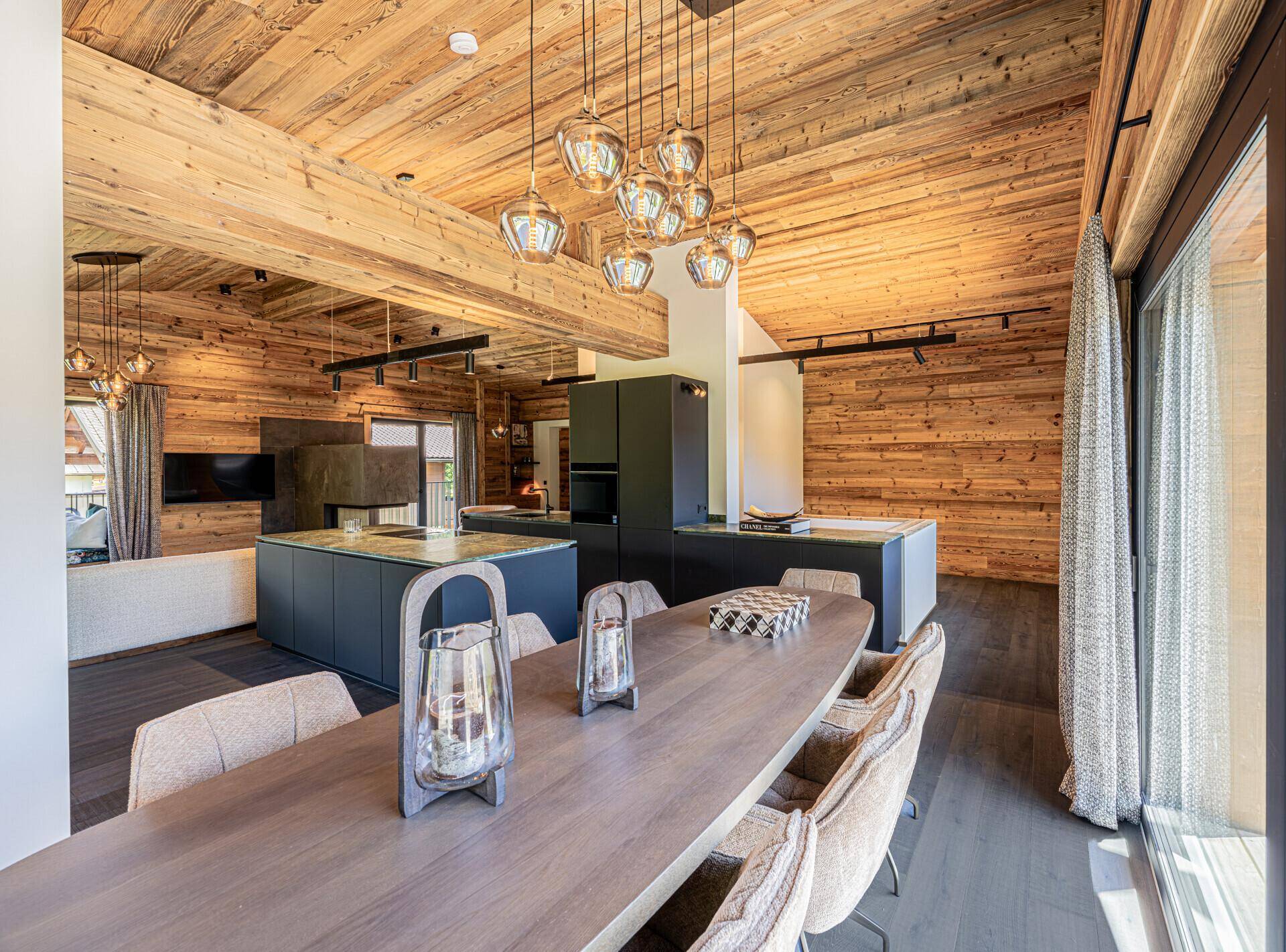 Eleganter Essbereich mit großem Holztisch, bequemen Stühlen und Zugang zur Terrasse.