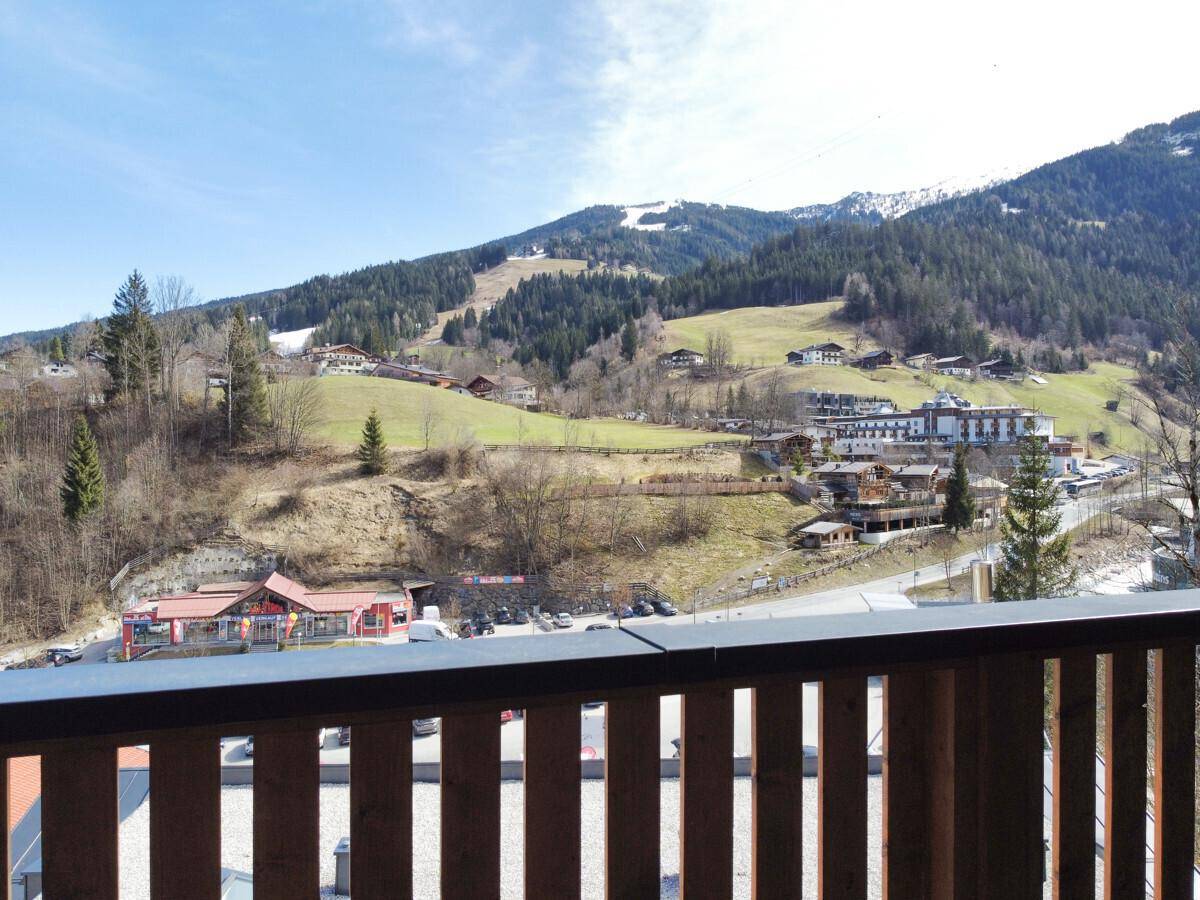Panoramablick vom Balkon auf die umliegende Berglandschaft, ein Dorf und eine Skipiste.