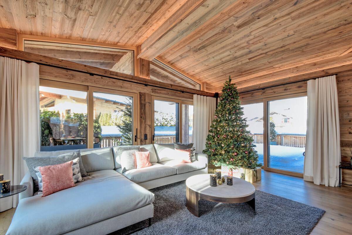 Gemütliches Wohnzimmer mit großem Sofa, Weihnachtsbaum und Zugang zur Terrasse.