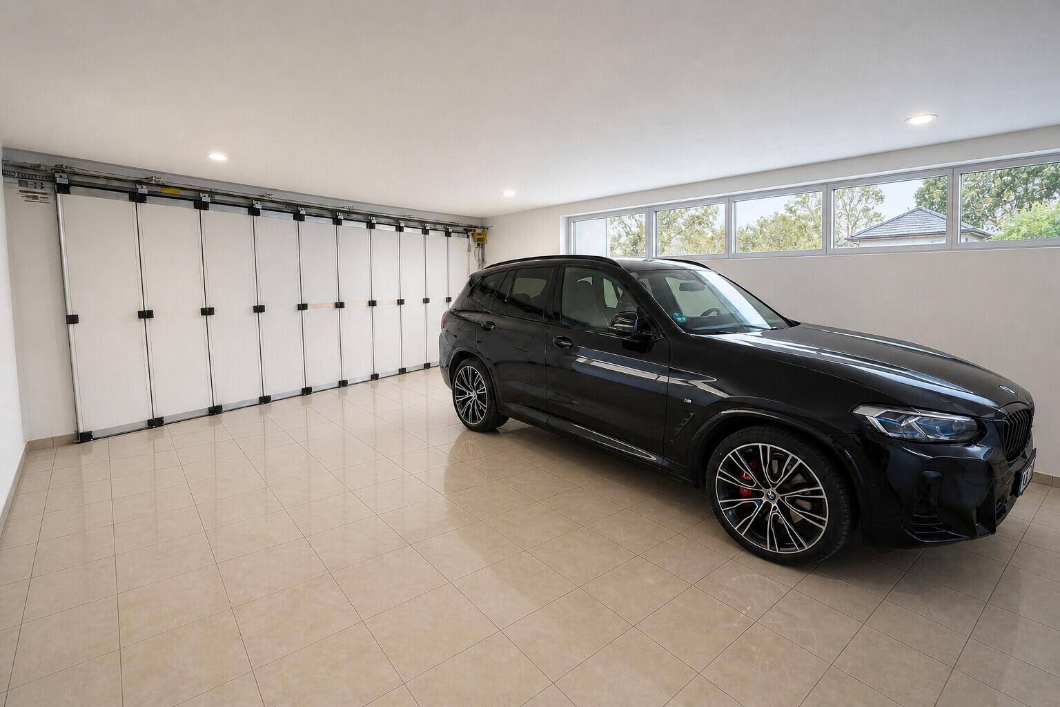Saubere und helle Garage mit Fliesenboden und einem geparkten schwarzen SUV.