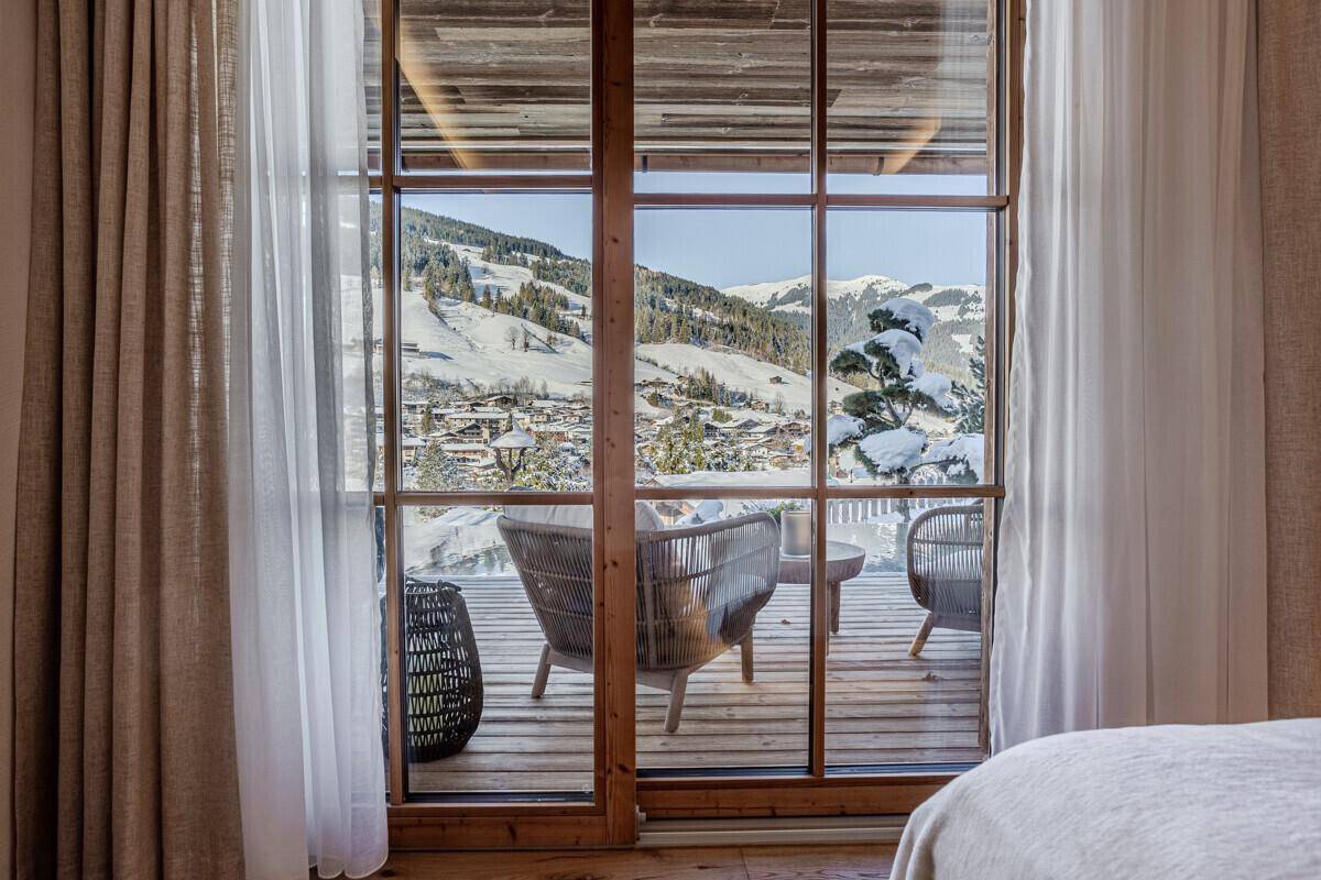 Helles Zimmer mit Zugang zu einem Balkon und Panoramablick auf die verschneite Berglandschaft.