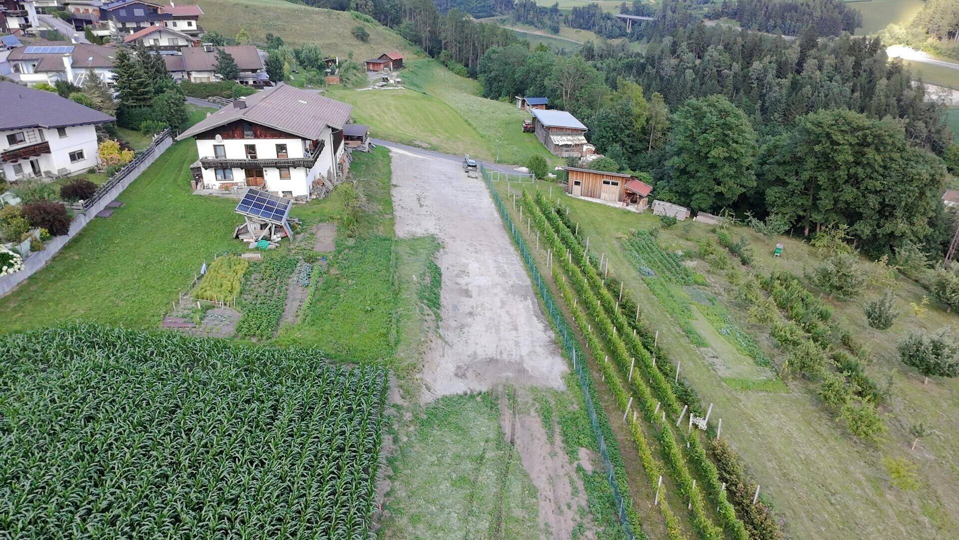 Luftaufnahme einer ländlichen Gegend mit Feldern, Weinbergen und einem Solarsystem auf einem Dach.