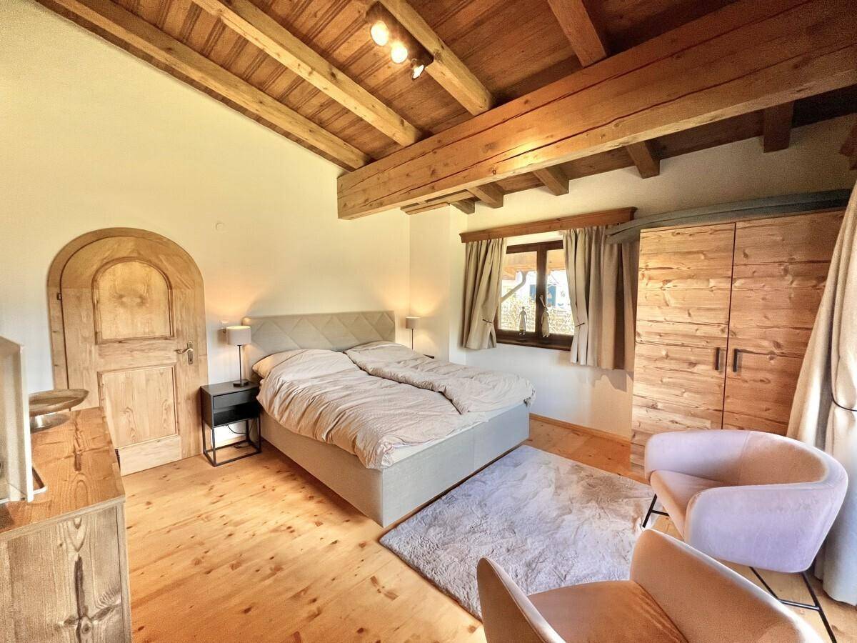 Schlafzimmer mit Holzbalkendecke, Doppelbett und einer traditionellen Holztür.