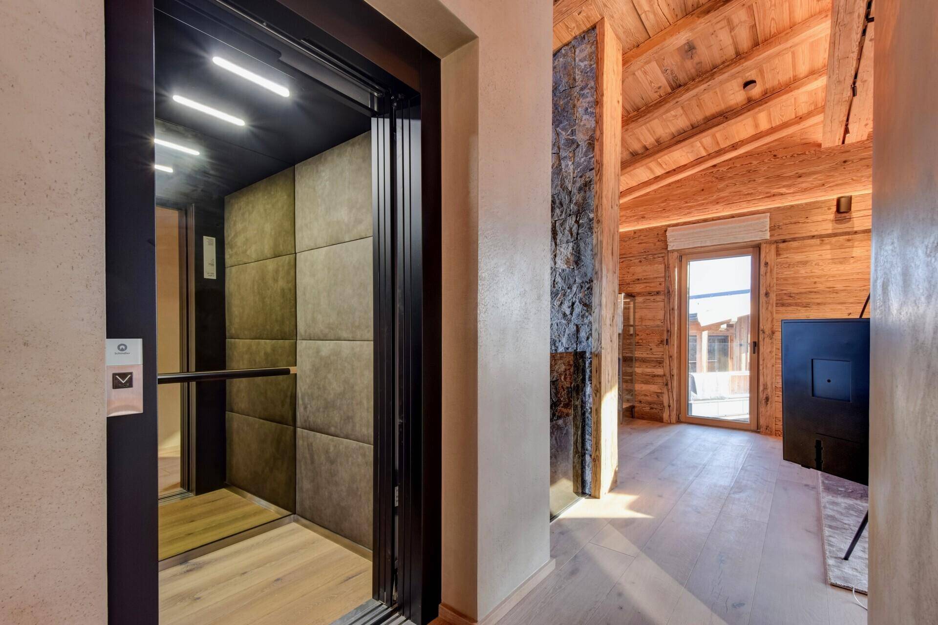 Moderner Aufzug in einem eleganten Flur mit Holzboden und Steinwand, stilvoll und funktional.
