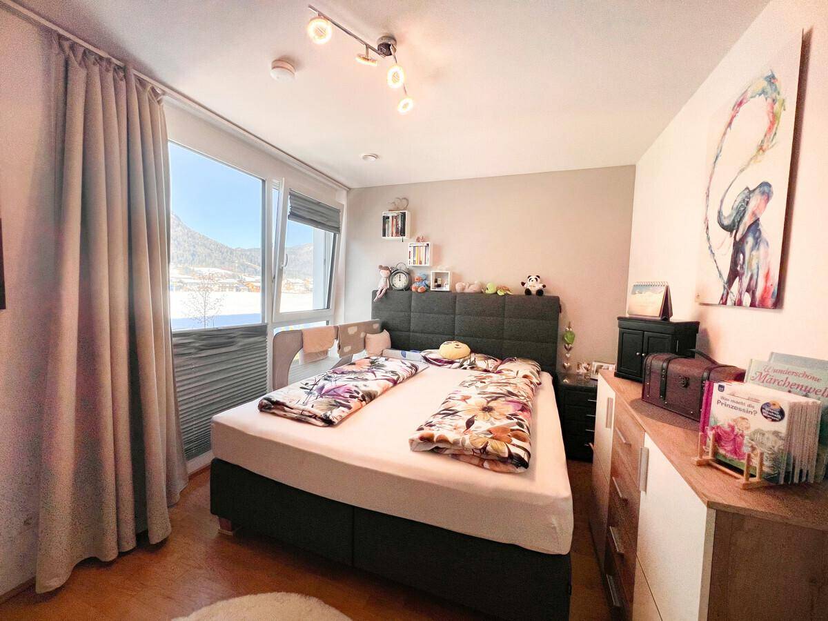 Schlafzimmer mit Holzboden, großem Fenster und einer malerischen Aussicht auf die umliegende Berglandschaft.