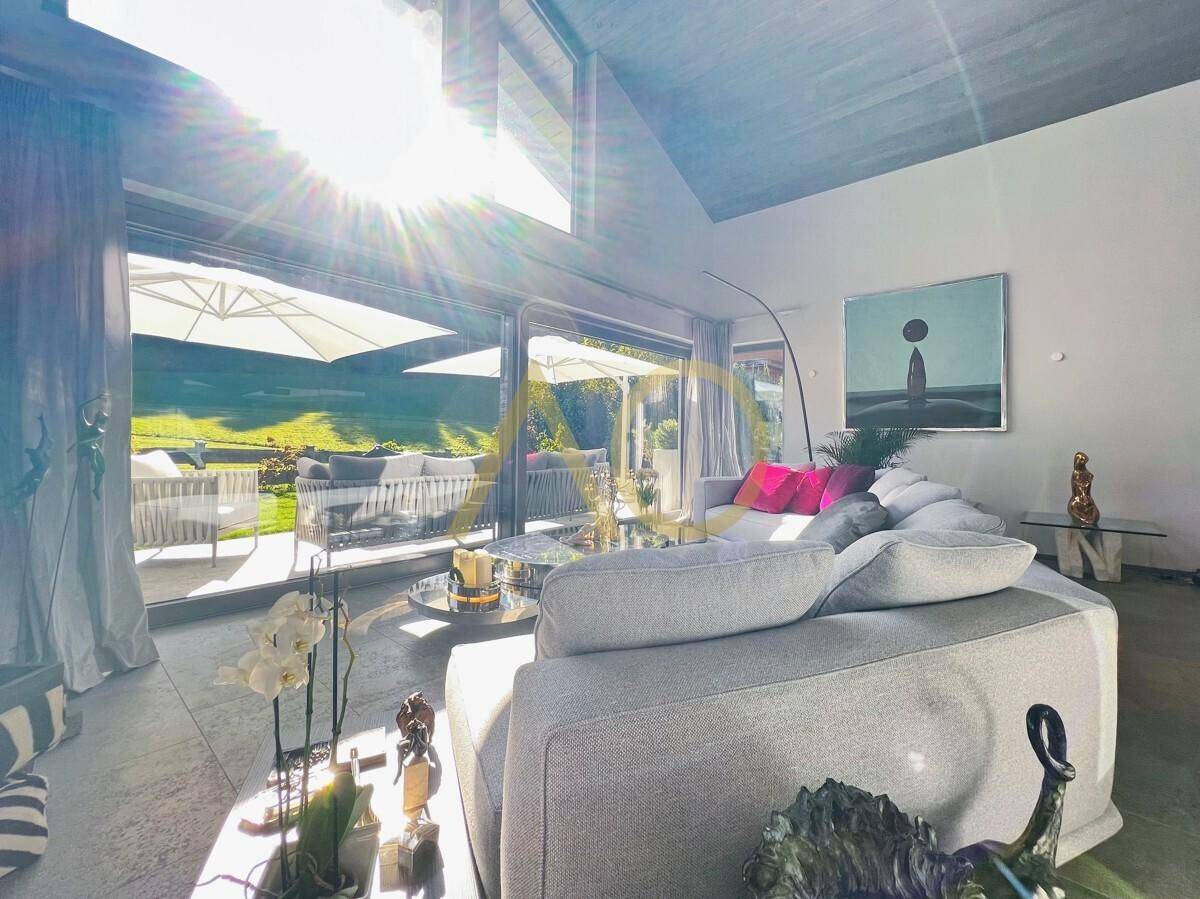 Lichtdurchflutetes Wohnzimmer mit großen Fensterfronten und direktem Zugang zur Terrasse.