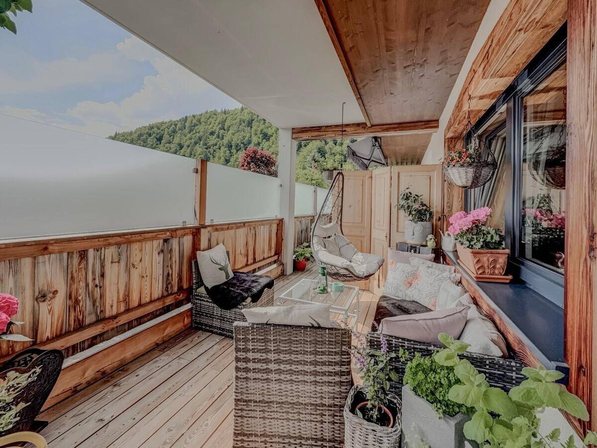 Überdachte Loggia mit bequemen Loungemöbeln, Hängesessel und Blick auf die Berge.