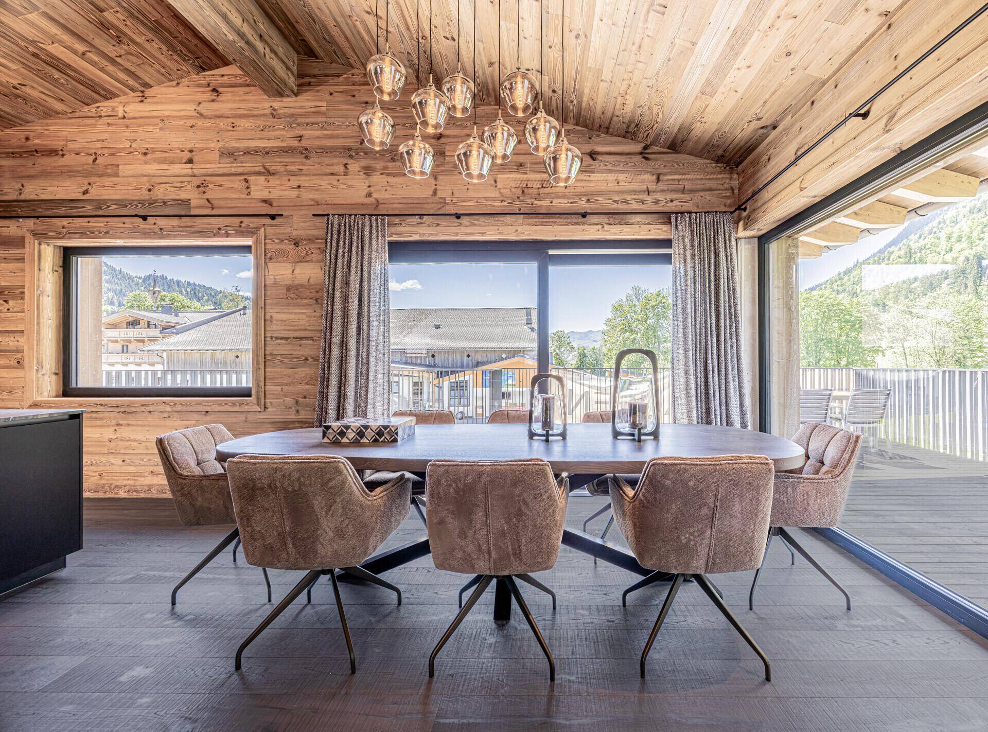 Eleganter Essbereich mit großem Holztisch, bequemen Stühlen und Zugang zur Terrasse.