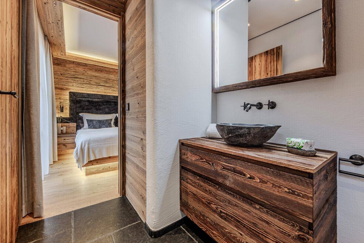 Modernes Ensuite-Badezimmer mit Steinwaschbecken und Holzelementen, direkt vom Schlafzimmer zugänglich.