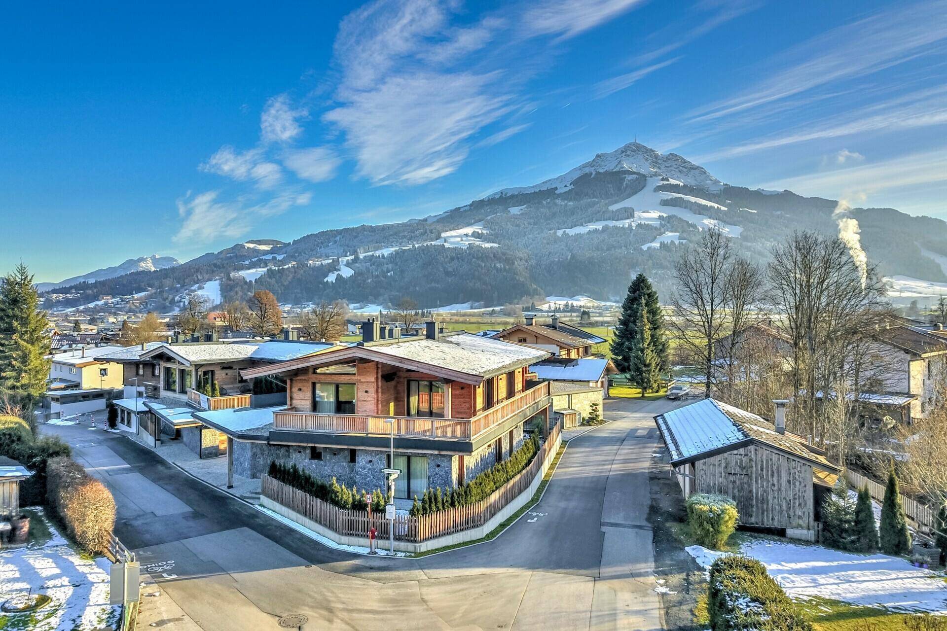 Panoramablick auf ein modernes Chalet in alpiner Landschaft mit schneebedeckten Bergen.