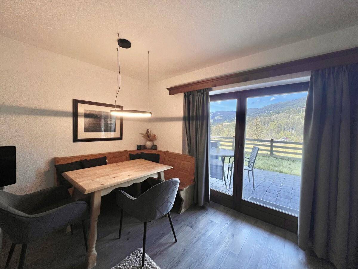 Essbereich mit Holztisch, Sitzbank und direktem Zugang zur Terrasse mit Bergblick.