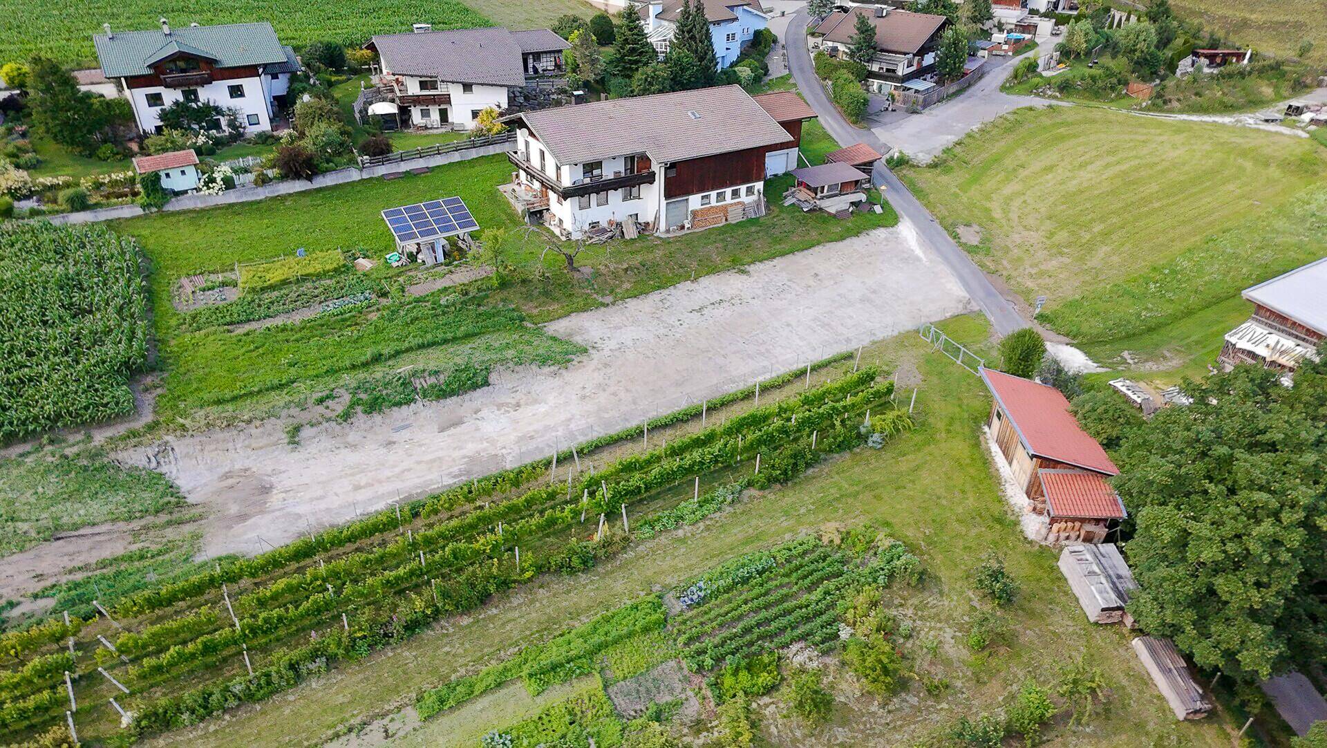 Luftaufnahme eines Anwesens mit Wohnhaus, landwirtschaftlichen Flächen und Weinreben.