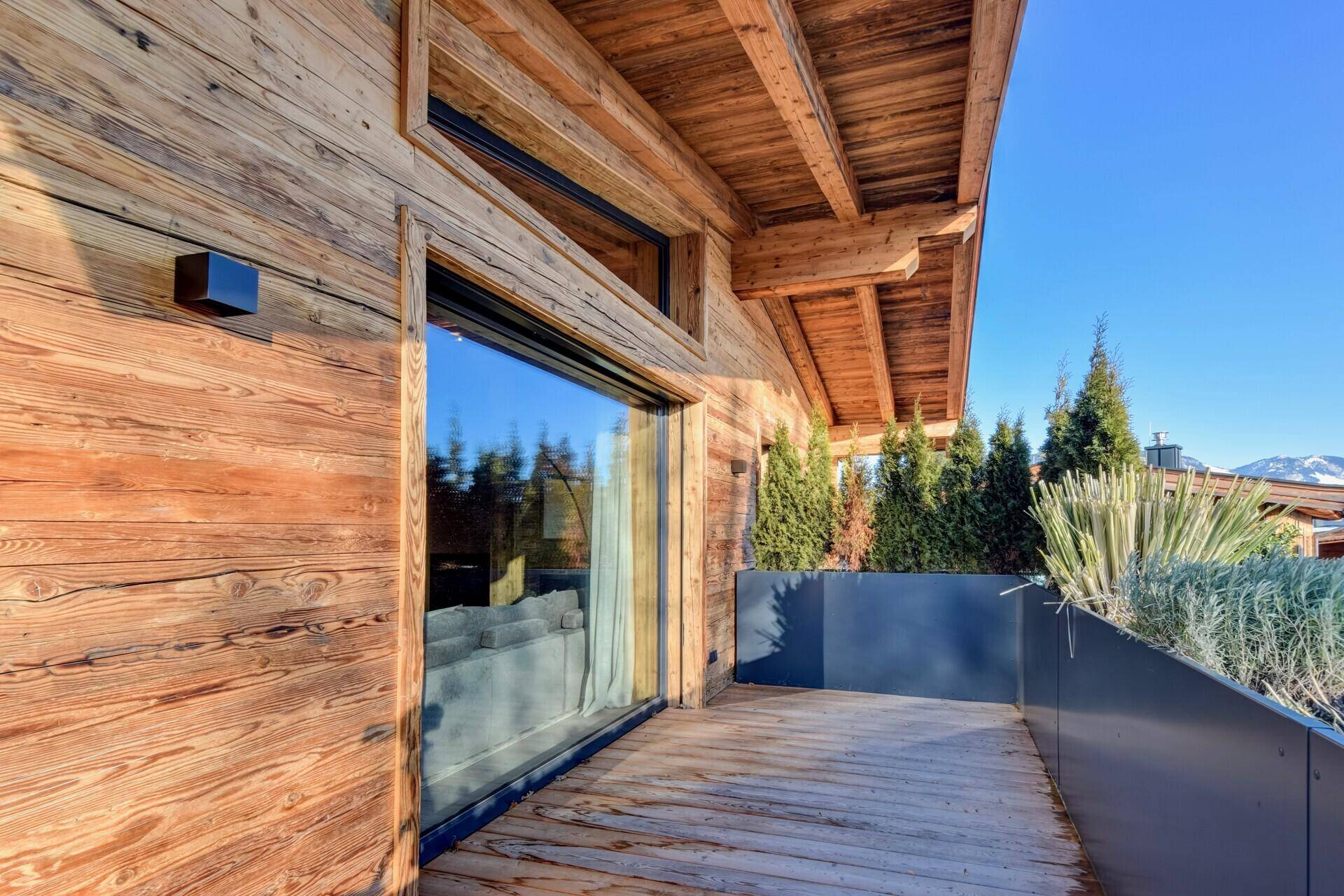 Sonniger Holzbalkon mit Pflanzen und Bergblick, ideal zum Entspannen im Freien.