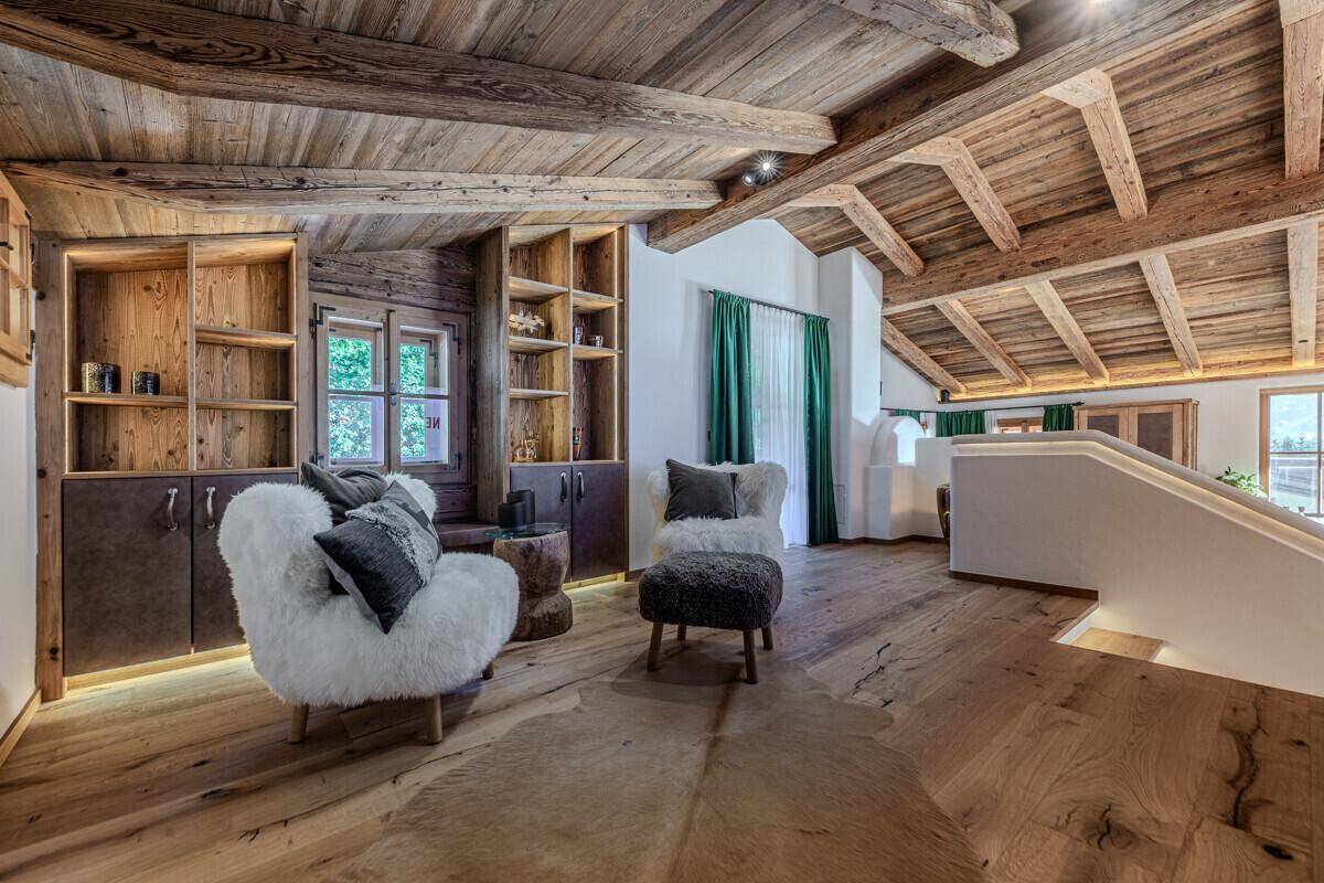 Gemütlicher Lounge-Bereich mit flauschigen Sesseln, Holzbalkendecke und eingebauten Regalen.
